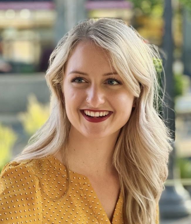 Dr. Amber Peterson smiling in a mustard yellow blouse.
